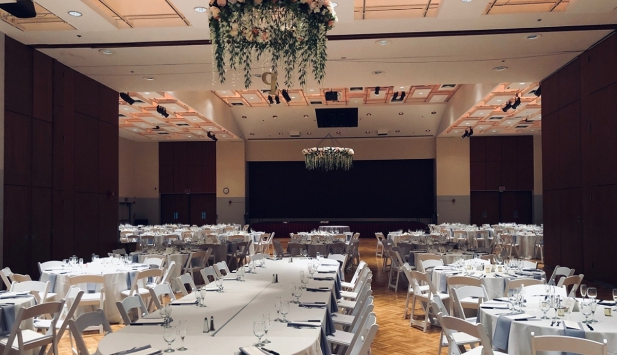 Student Center ballrooms.  White chairs with white tables.  Handing flowers from ceiling